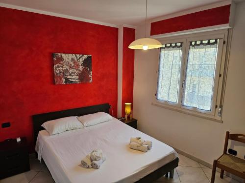 Un dormitorio con paredes rojas y una cama con toallas. en #voglioandareadalghero, en Alghero