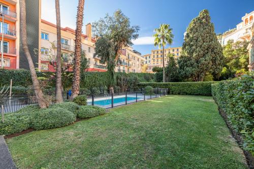 un jardin avec une piscine, des arbres et des bâtiments dans l'établissement Inter Superb Studio Piscine 5 min gare, à Menton