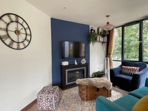 a living room with a large clock on the wall at The Urban Green! Cosy luxury apartment in Chiswick in London