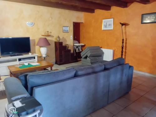 un salon avec un canapé bleu et une télévision dans l'établissement Location Thezacaise, à Thézac