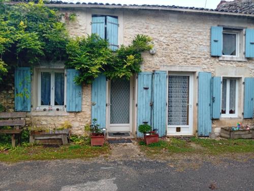 une ancienne maison en pierre avec des volets bleus et des plantes en pot dans l'établissement Location Thezacaise, à Thézac