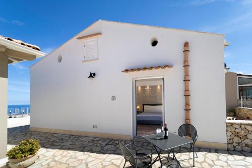 a white house with a patio with a table at Hotel Antica Cascina Del Golfo in Scopello