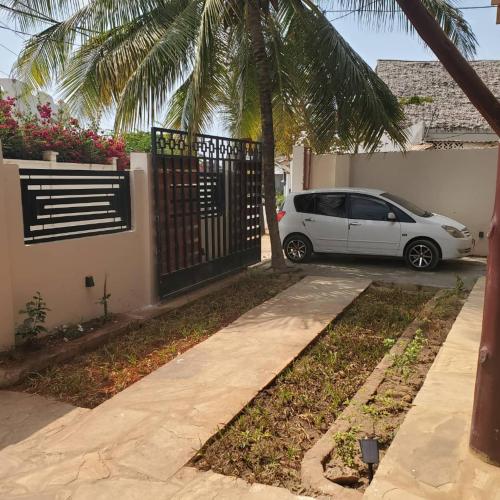 a white car parked next to a house with a gate at Sand and Sunset in Kendwa