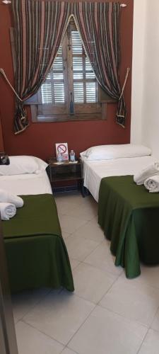 a bedroom with two beds and a window with curtains at Casa los Tres Aires in El Rocío