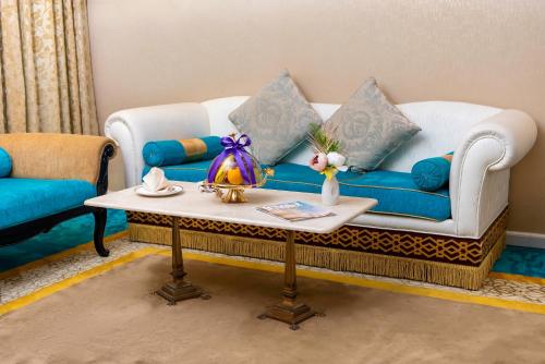 a living room with a blue couch and a table at Saraya Corniche Hotel in Doha