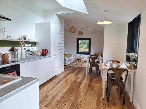 a kitchen with white cabinets and a table with chairs at Le Clos du Palastre, à 10 mn de Vannes in Plescop