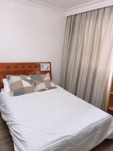 - un lit avec des draps et des oreillers blancs à côté d'une fenêtre dans l'établissement Paris Appartement luxe inclus parking - Quai de la Seine -opéra 15mins, à Paris