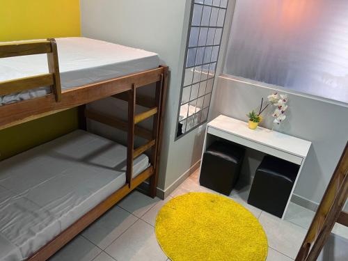 a small room with two bunk beds and a yellow rug at Jambu Hostel Belém in Belém