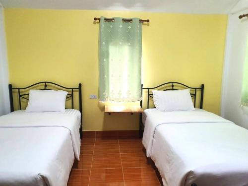 two beds in a room with a window at บ้านชมดาวรีสอร์ทบึงโขงหลง in Ban Don Klang