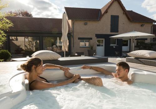 a man and a woman sitting in a hot tub at Hôtel de France in Montmarault