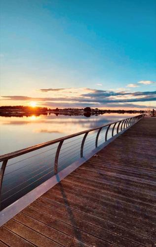 a bridge over a body of water with the sunset at Abri du pêcheur in Étel