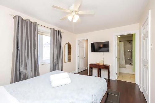 a white bedroom with a bed and a ceiling fan at Cozy Modern 4BR Home with Sunny Patio in Ottawa