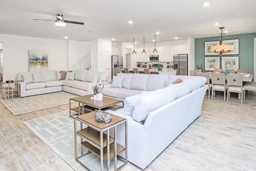 a living room with a white couch and a table at Upstay - Magic Mansion w Pool-Spa-Cinema-Games in Kissimmee