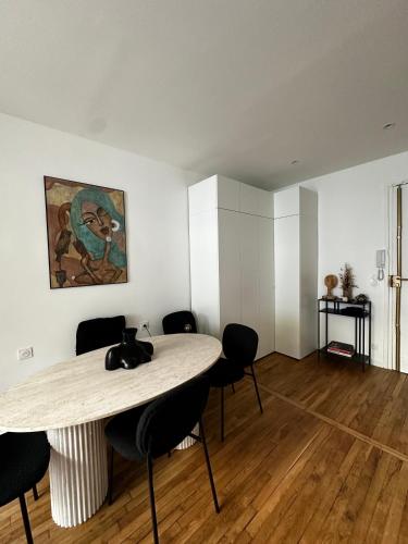 Cette chambre comprend une table avec des chaises et un tableau mural. dans l'établissement Appartement avec terrasse, à Paris