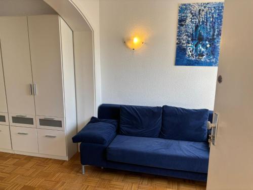eine blaue Couch in einem Wohnzimmer mit einem Gemälde in der Unterkunft Für Handwerker und Gruppen- große Ferienwohnung mit Balkon und Terrasse in Bad Dürrheim