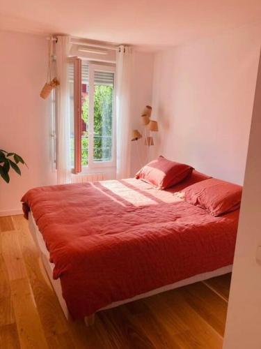 - une chambre avec un lit doté de draps rouges et une fenêtre dans l'établissement Bel appartement à Pantin avec balcon, à Pantin