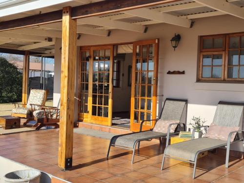 a patio with two chairs and a porch at Meadow View Guest Room in Wakkerstroom