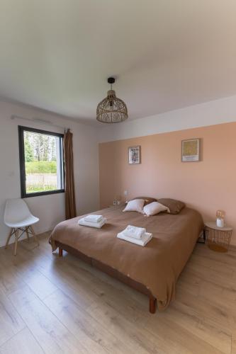 une chambre avec un grand lit avec deux serviettes dessus dans l'établissement Jolie Maison avec piscine intérieure à 5 minutes des plages, à Landunvez