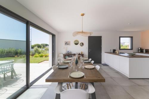ein großes Esszimmer mit einem Tisch und einer Küche in der Unterkunft Jolie Maison avec piscine intérieure à 5 minutes des plages in Landunvez