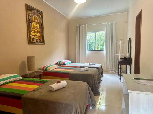 a room with three beds with a buddha picture on the wall at Sitio Ingá in Guaramiranga