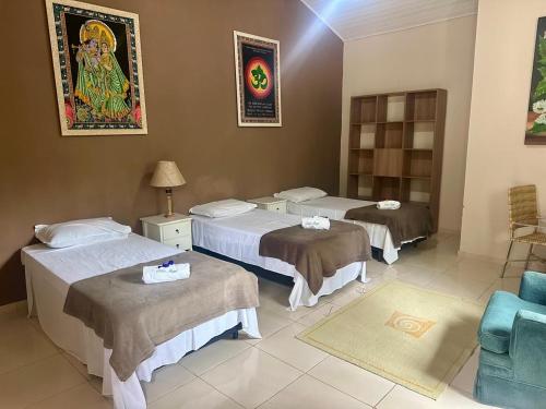 a hotel room with three beds and a chair at Sitio Ingá in Guaramiranga
