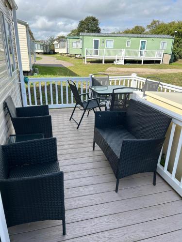 a deck with chairs and a table on a house at Holiday home cherry tree Burgh castle Great Yarmouth in Belton