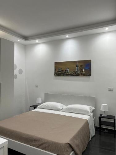 a white bedroom with a large bed and two tables at Dimora al Centro in Cosenza