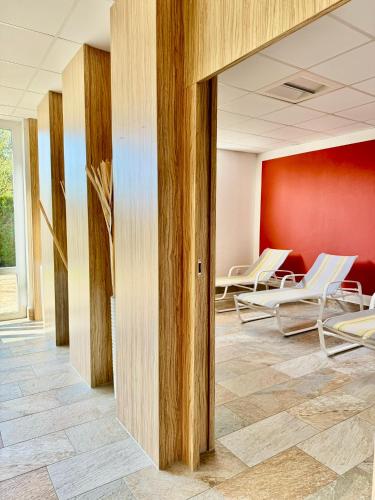 a waiting room with white chairs and a red wall at JJ Living - Alpenblick 073 in Scheidegg