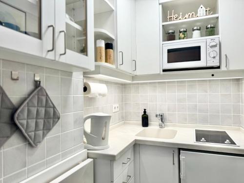 a white kitchen with a sink and a microwave at JJ Living - Alpenblick 073 in Scheidegg