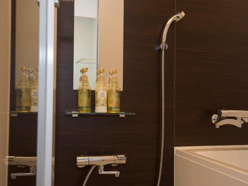 a bathroom with a shower with bottles on a shelf at Hotel Bokaiso in Takamatsu