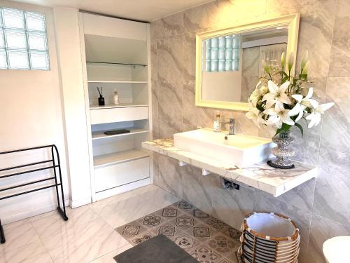 a bathroom with a sink and a vase of flowers at Greenhouse Villa in Kerobokan
