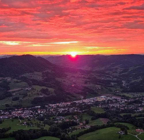 a sunset over a city with the sun in the sky at Loftartige Wohnung in Scheibbs mit Schwimmteich in Scheibbs