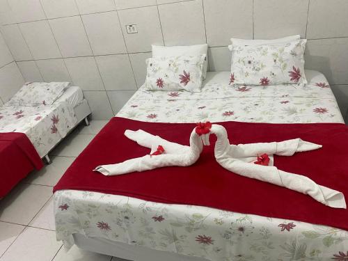 two beds with two people laying on them on a red blanket at Casa da Cida in Fernando de Noronha