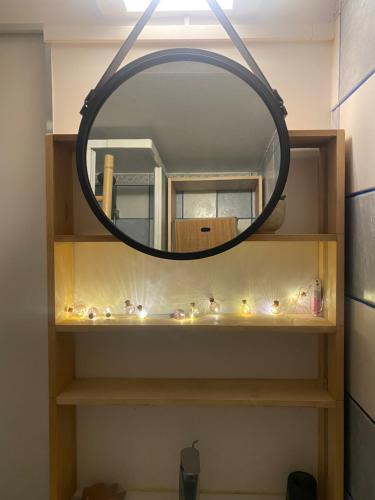 - un miroir de salle de bains avec des lumières sur une étagère dans l'établissement Appartement cosy proche Tour Eiffel, à Paris