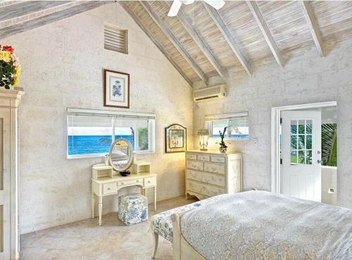 a bedroom with a bed and a desk and windows at Ocean Mist Villa 4Bd by ZenBreak in Saint Philip