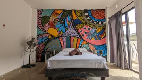a bedroom with a painting on the wall at Garden House Puerto López in Puerto López