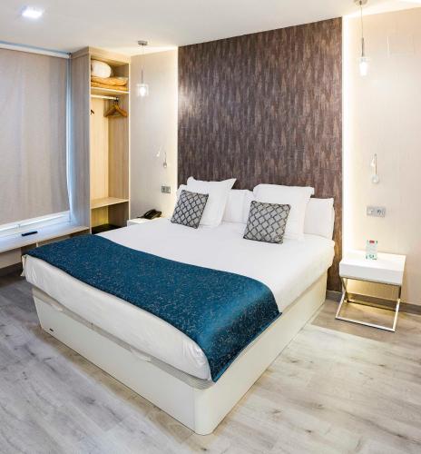 a bedroom with a large white bed with a blue blanket at Bellavista Sevilla in Seville