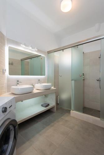 a bathroom with two sinks and a glass shower at Fidopo Houses in Chrisopigi