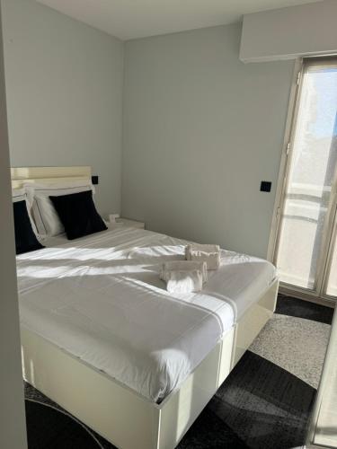 un grand lit blanc dans une chambre avec une fenêtre dans l'établissement 3 pièces avec vue mer à 5 min de la gare et 10 min du centre, à Beausoleil