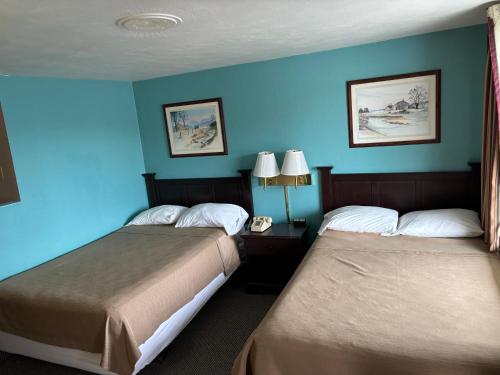 two beds in a hotel room with blue walls at Budget Host Inn Somerset in Somerset