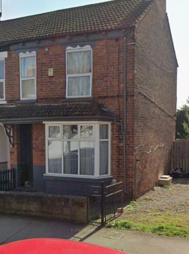 a brick house with white windows and a gate at Ella street Double room in Hull
