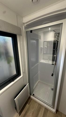 La salle de bains est pourvue d'une douche à l'italienne à côté d'une fenêtre. dans l'établissement Mobil-home neuf tout confort - Camping 4 étoiles les sables d or - Le Cap d Agde, au Grau-dʼAgde