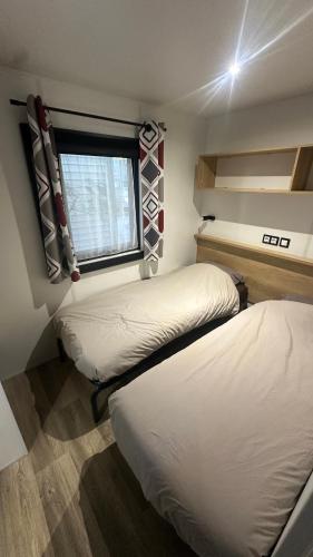 deux lits dans une petite pièce avec une fenêtre dans l'établissement Mobil-home neuf tout confort - Camping 4 étoiles les sables d or - Le Cap d Agde, au Grau-dʼAgde