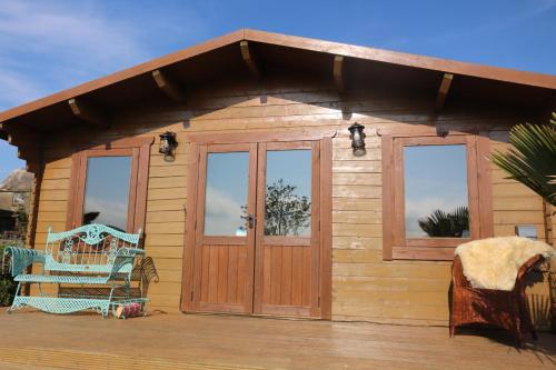 a wooden cabin with glass doors and a chair on a deck at The Cabin Pipershill in Newtown Butler