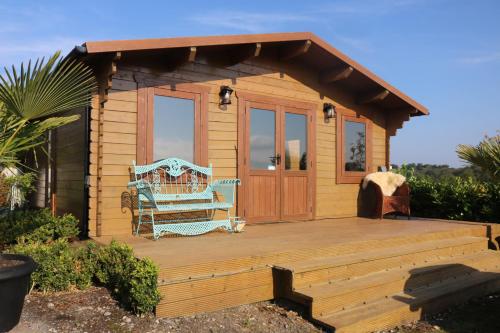 a small cabin with a bench on a wooden deck at The Cabin Pipershill in Newtown Butler