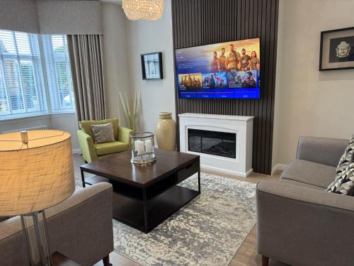 a living room with a tv above a fireplace at Luxury 2 Bedroom Cottage in West Calder