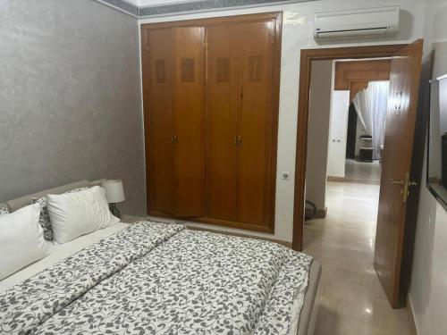 a bedroom with a bed and a wooden cabinet at Beautiful cozy apartment with pool in Marrakesh