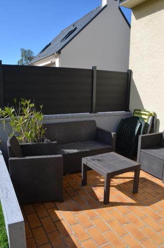 a patio with a bench and a table and chairs at Maison de la fontaine in Saint-Méloir-des-Ondes