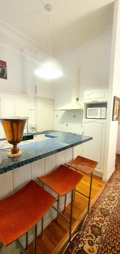 une cuisine avec un comptoir et deux bancs dans l'établissement Hortensia Appartement de Charme 92 m2 Hyper Centre - Down Town, à Boulogne-sur-Mer