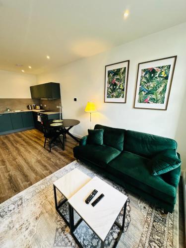 ダンファームリンにあるBarnet House Serviced Apartmentsの緑のソファとテーブルのあるリビングルーム